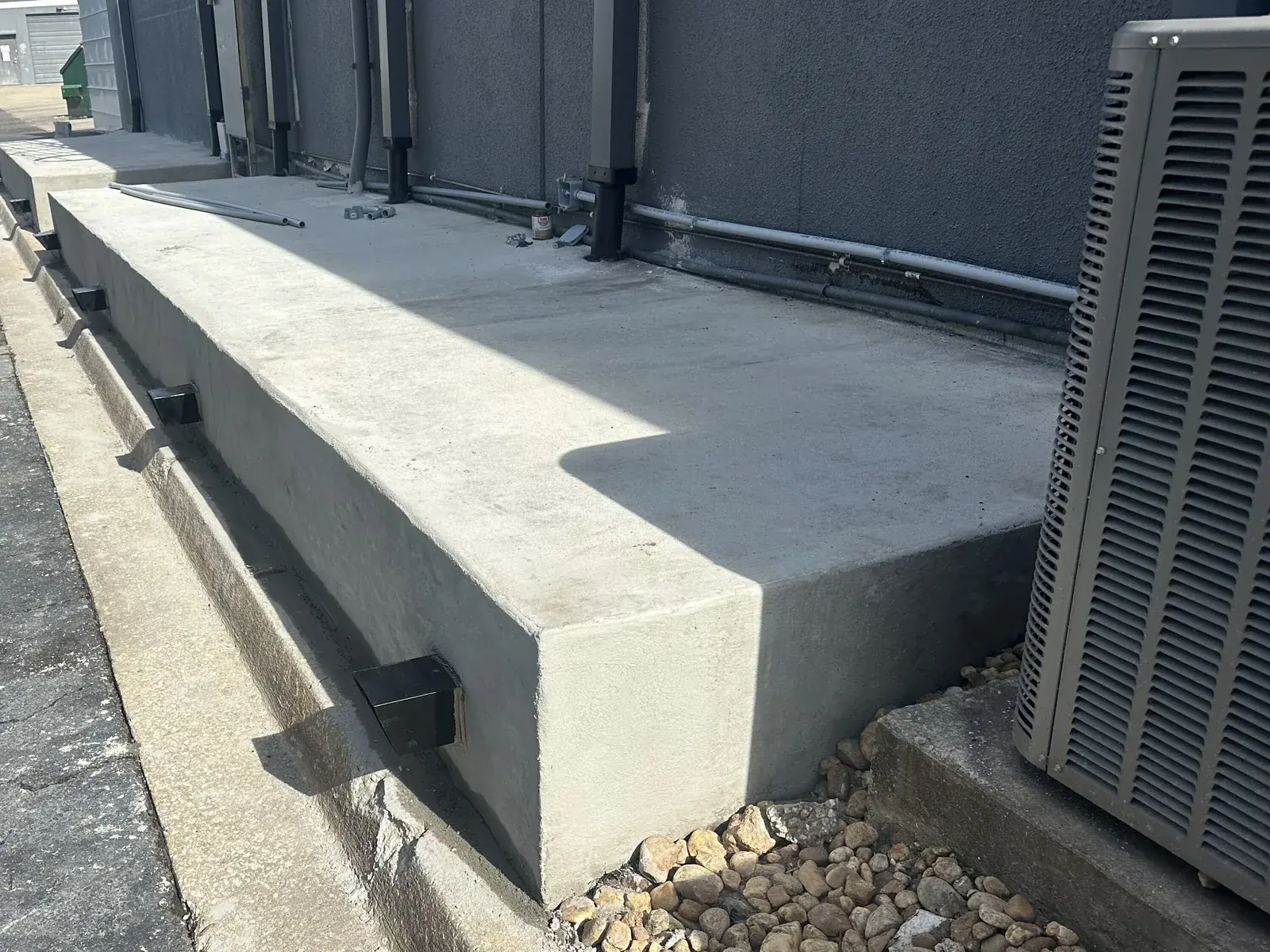 Raised concrete equipment platform poured along a commercial building