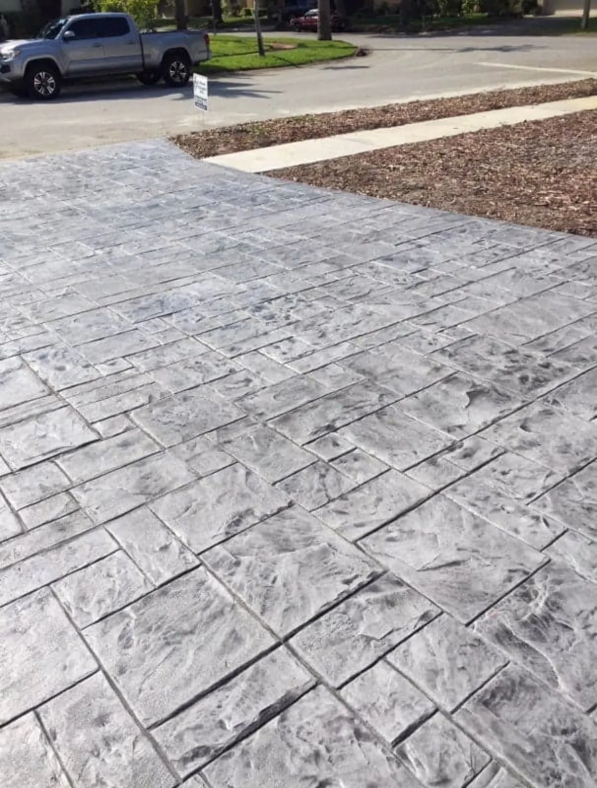 Gray ashlar slate stamped concrete driveway at the street