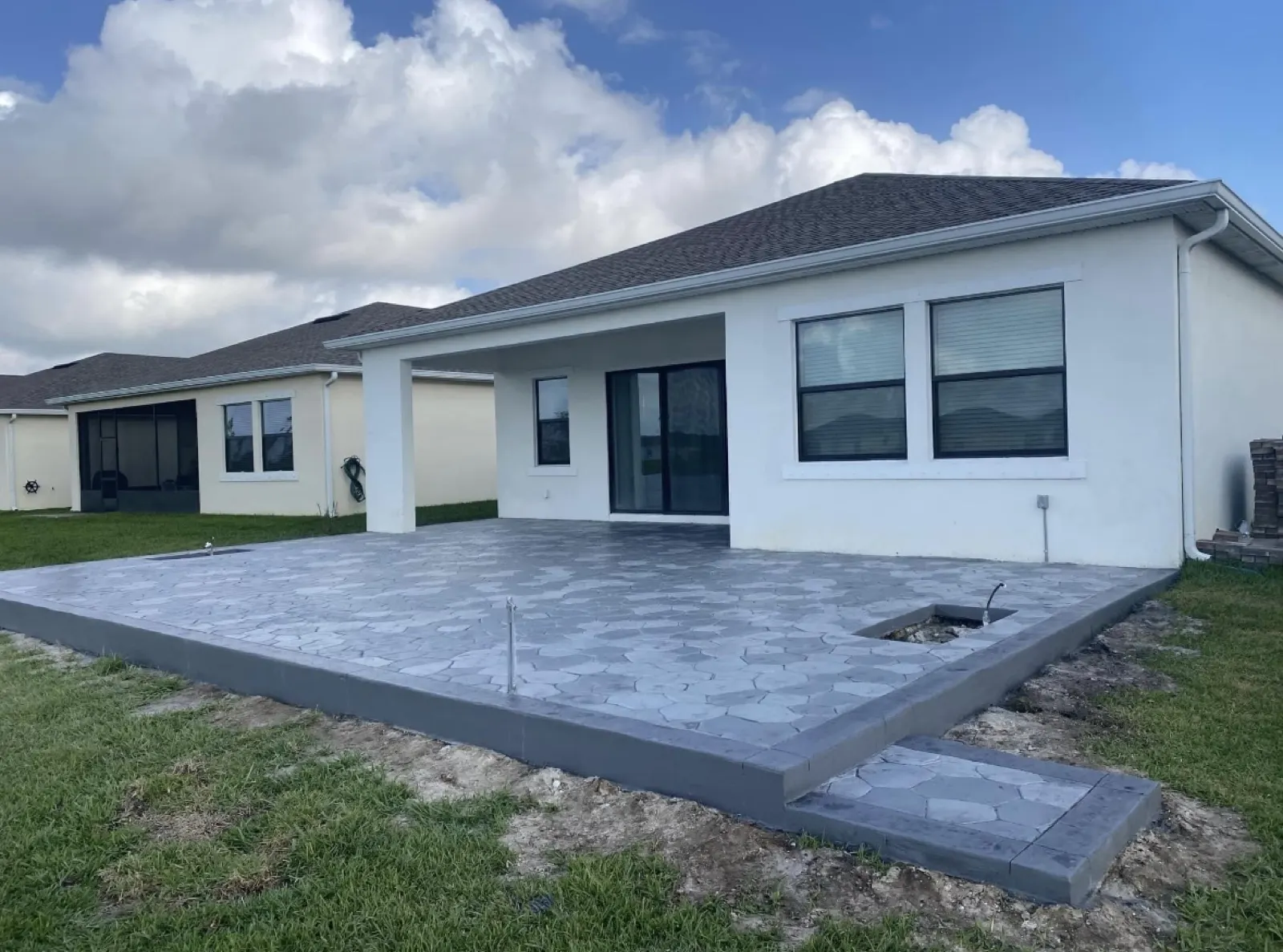 Gray flagstone pattern stamped concrete patio with a smooth border behind a new home
