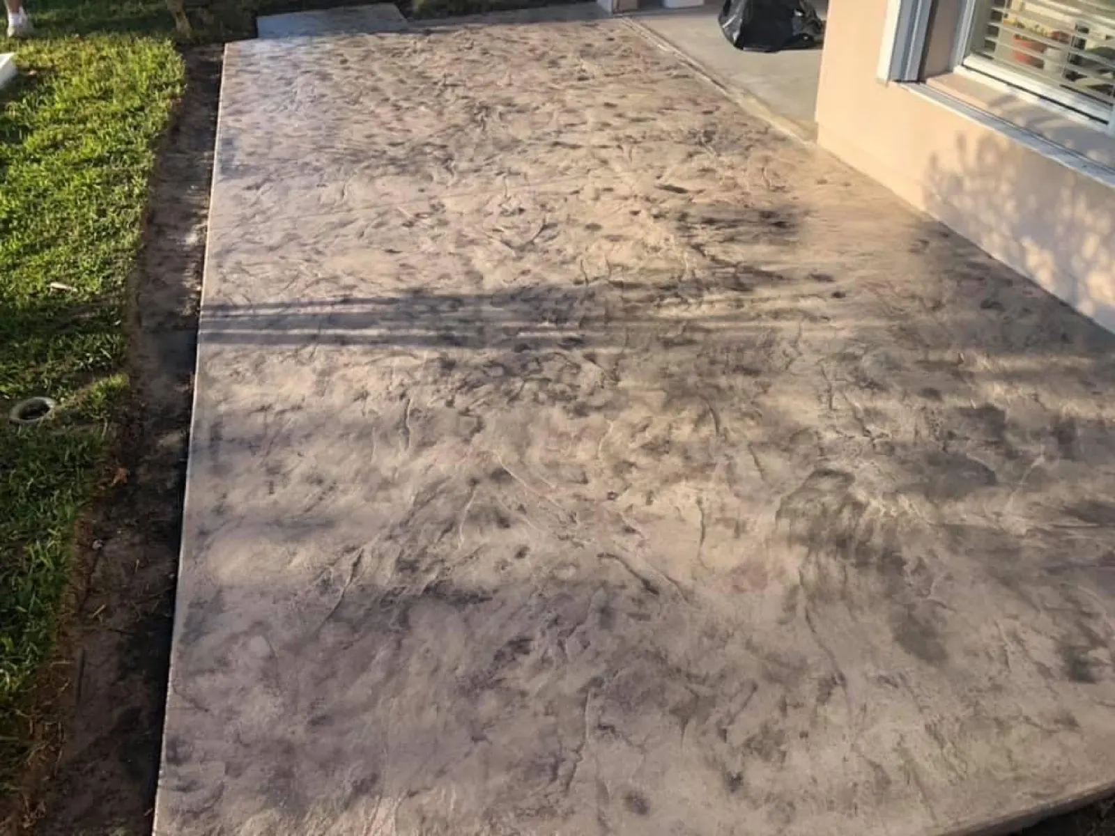 Seamless texture stamped concrete slab along the side of a home